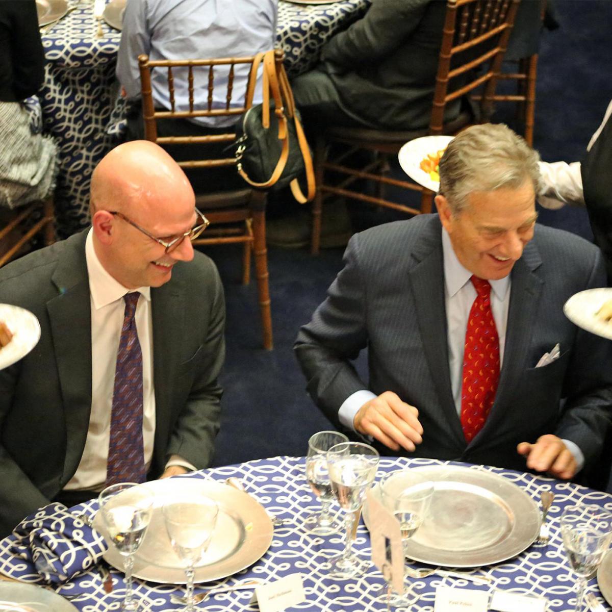 Joel Hellman and Paul Pelosi seated at a table during the scholars program at the SFS Board of Advisors Dinner in Riggs Library