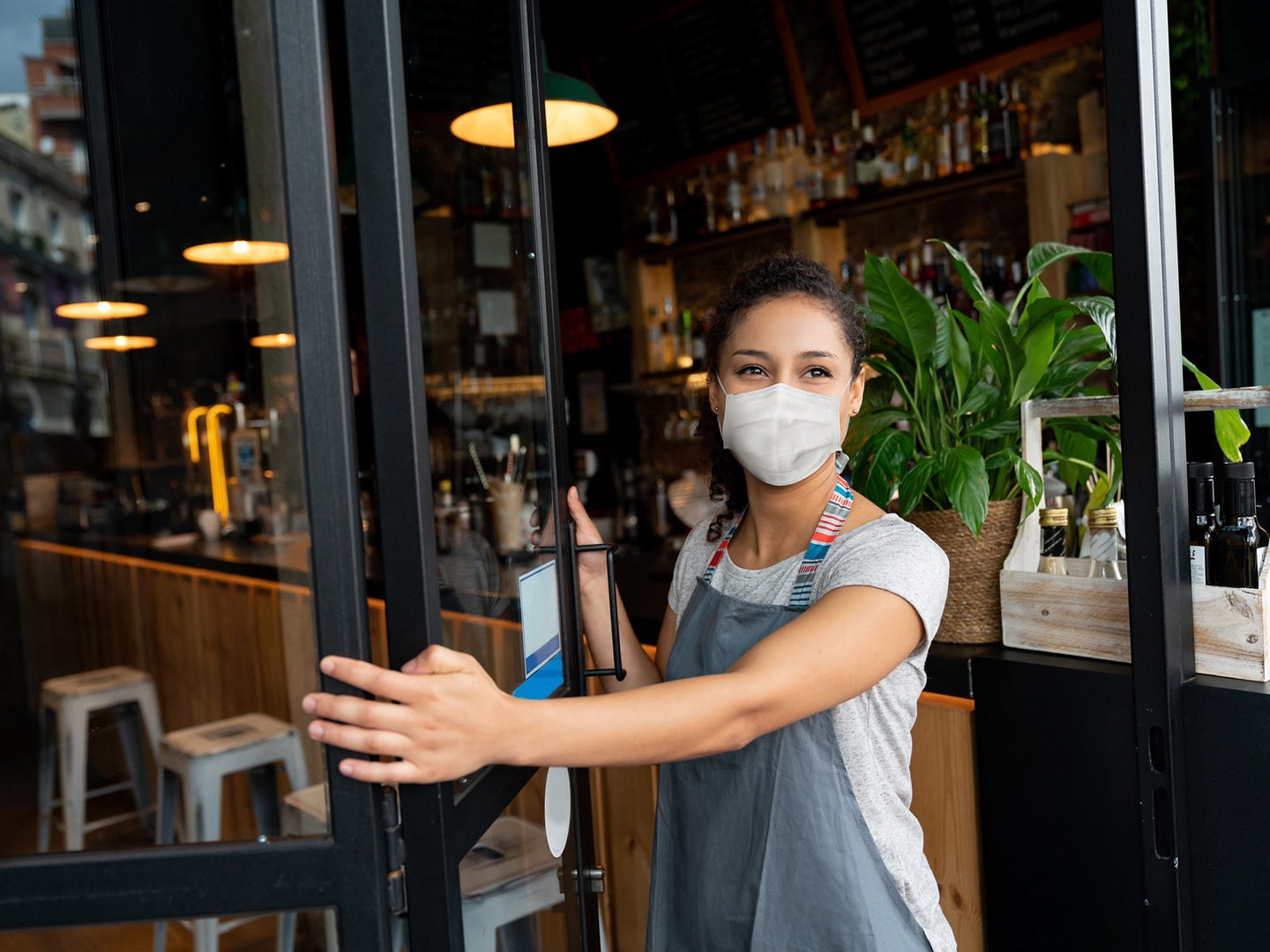 Young Latino lady with Mask opens the door