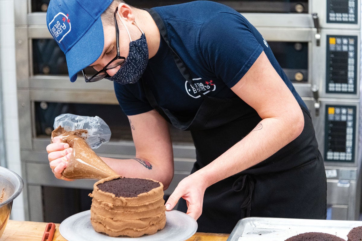 employee in mask frosting cake