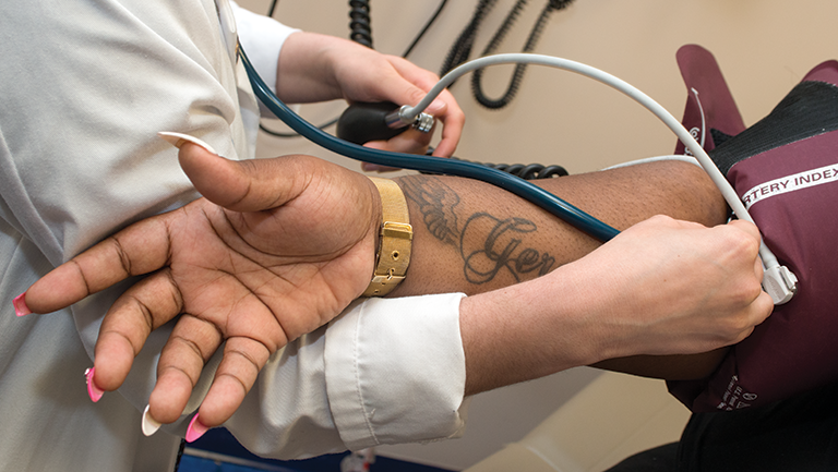 doctor putting stethoscope on patient's arm