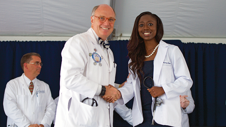 Lindsey Hastings-Spaine (M’19) shakes hands with Dean Mitchell at the White Coat Ceremony in August 2015