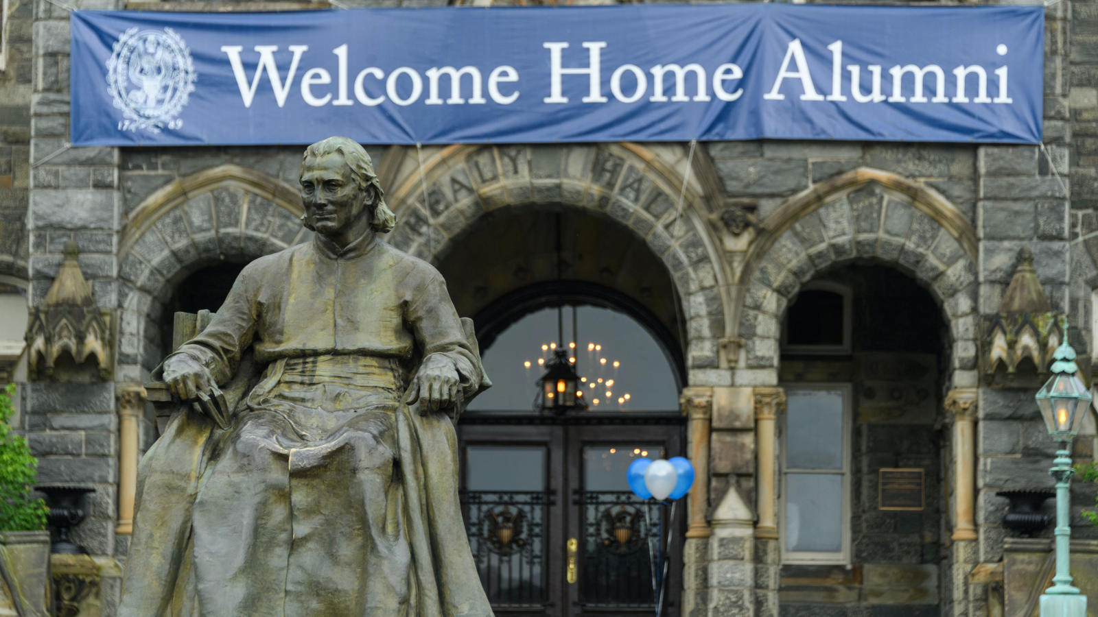 The John Carroll statue with a “Welcome Home Alumni” banner draped on Healy Hall for Reunion.