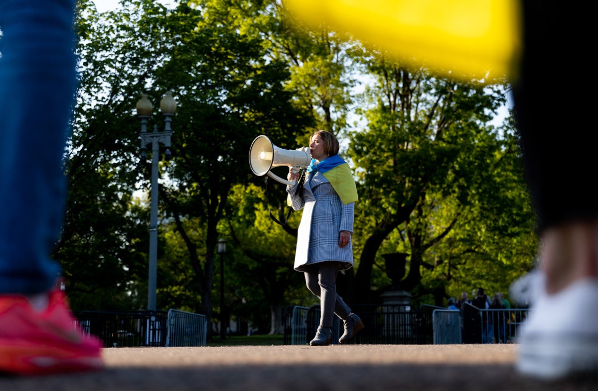 a woman stands with a bullhorn