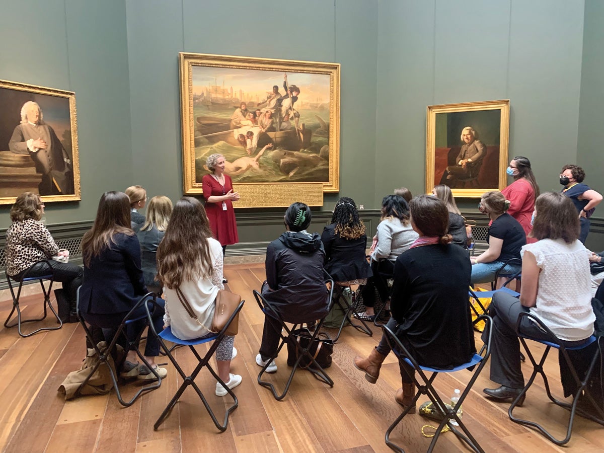 students sitting in an art gallery look at a painting