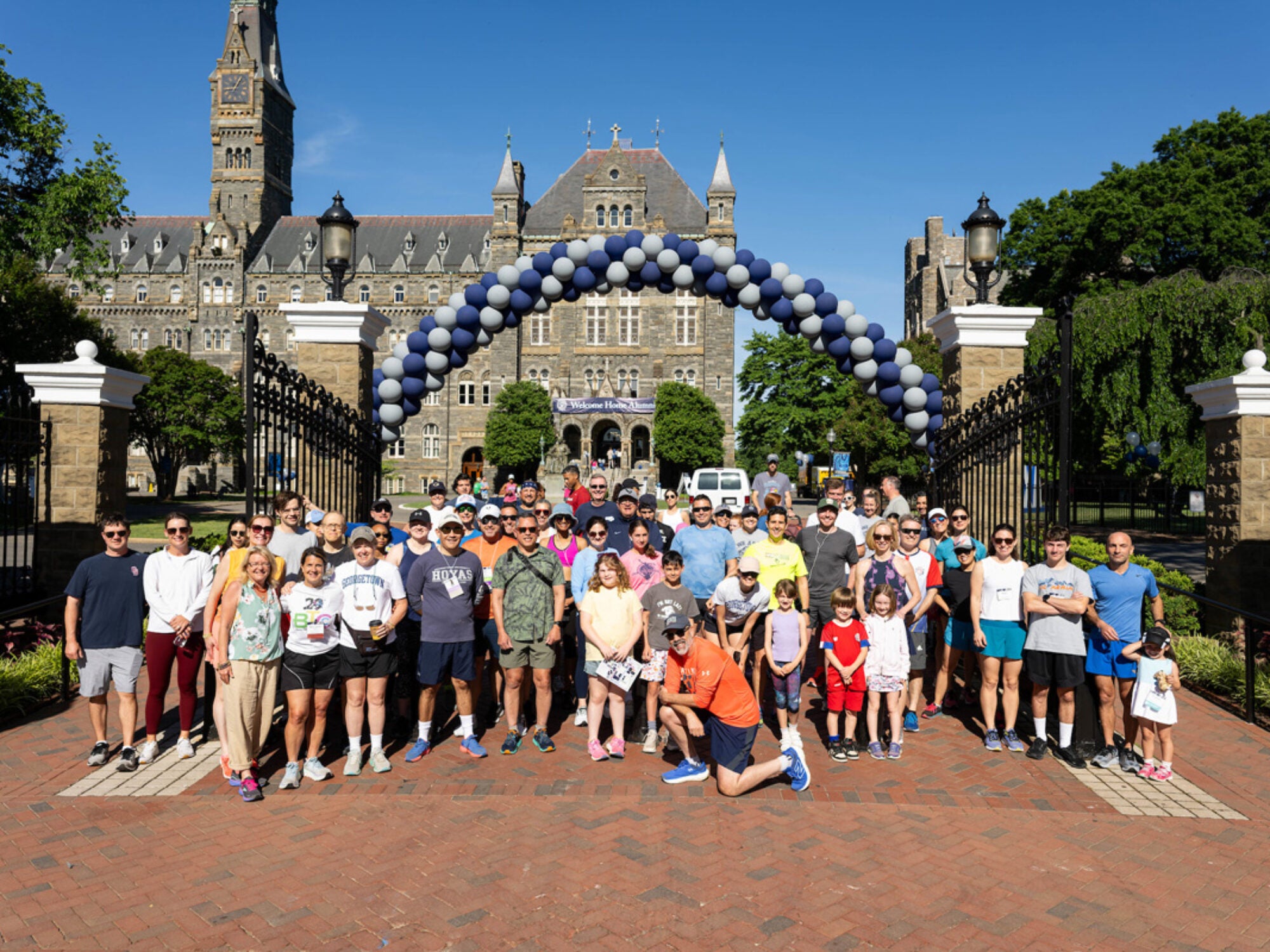 alumni posing outside front gates