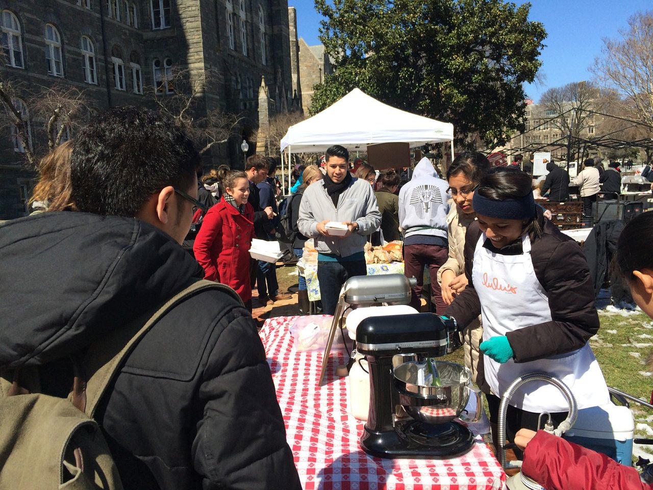 people are near a picnic table on the Georgetown campus, with an outdoor tent nearby