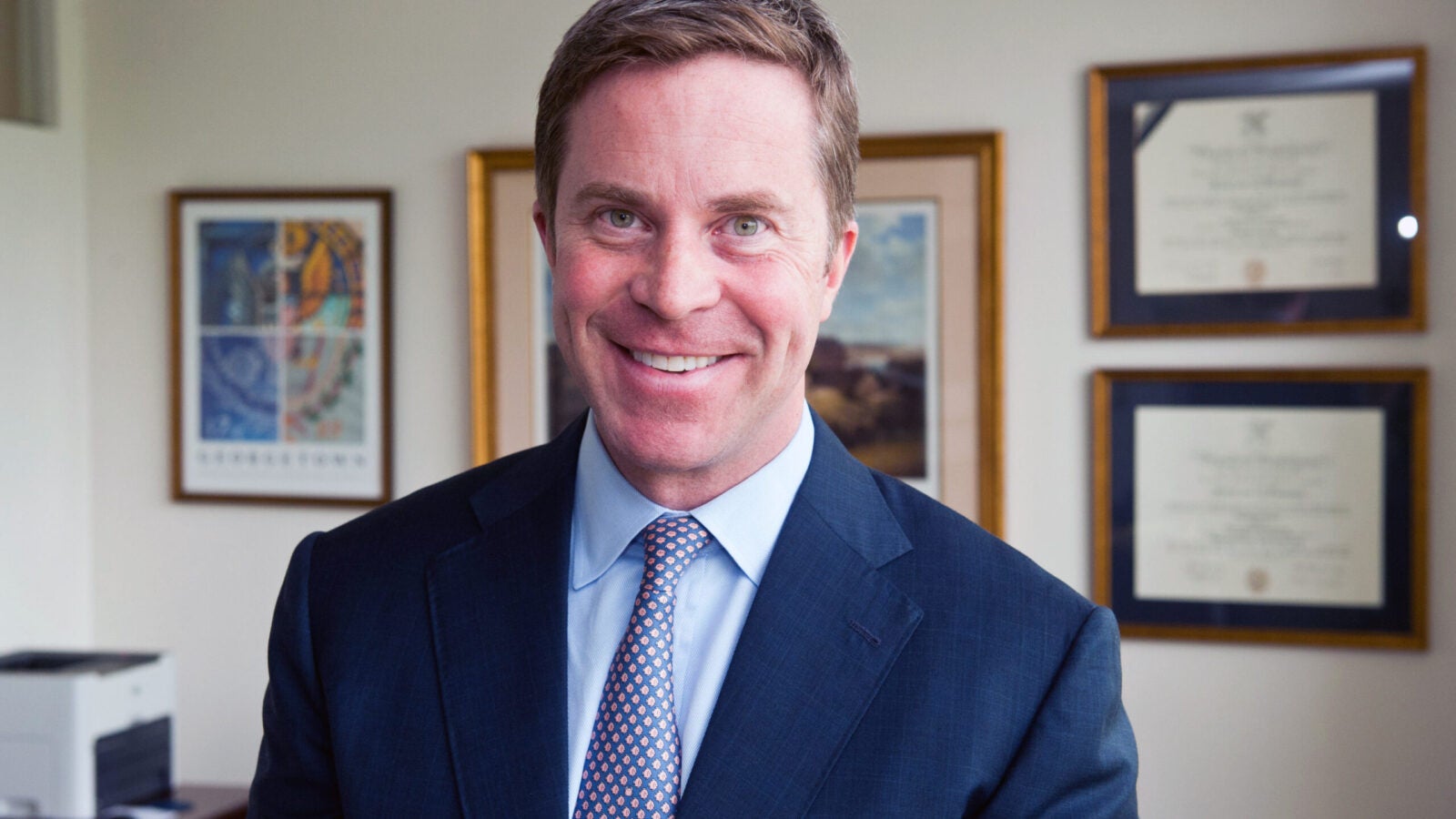 Photo of Paul O'Neill in front of a wall with photos.