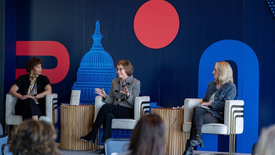 three women in chairs on a stage in front of a room full of people