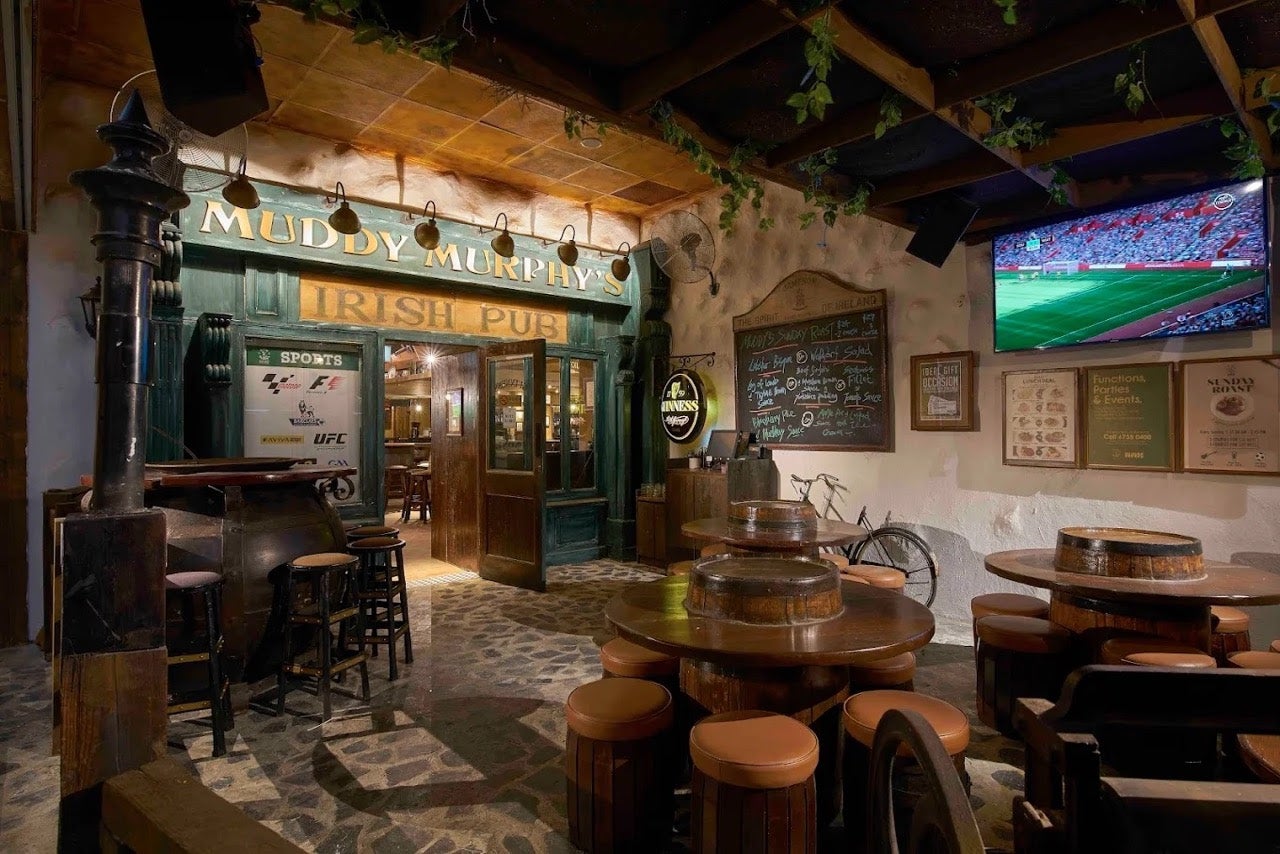 Entrance to Muddy Murphy's, an Irish Pub in Singapore. Wooden tables, stools, and doors fill the frame